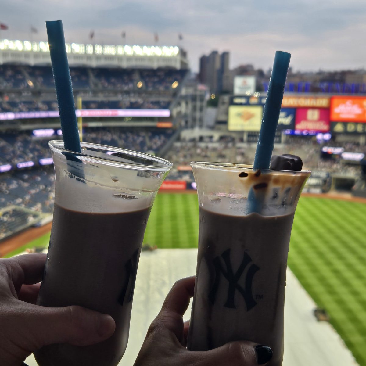 Two drinks raised over the field at Yankee Stadium