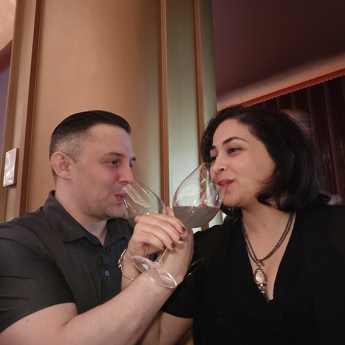 Nick and Nagham toasting with red wine at dinner